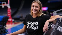 Smiling woman in black Hot Girls Hit Arby's t-shirt at indoor sports arena